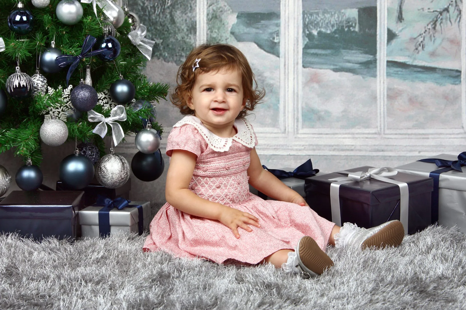 A nursery child by a festive Christmas tree